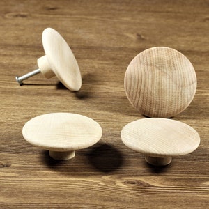 May include: Four wooden knobs with a round, flat top and a small, round base. The knobs are light brown in color and have a smooth, polished finish.
