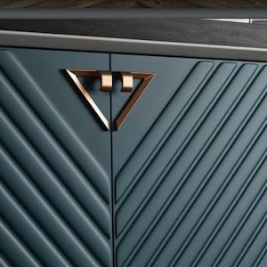 Puede incluir: Una cómoda azul oscuro con cuatro cajones. Los cajones tienen un patrón geométrico y tiradores en forma de triángulo dorado.