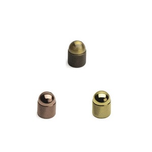 May include: Three metal knobs with a round top and a knurled base. The knobs are in antique brass, polished brass, and copper finishes.