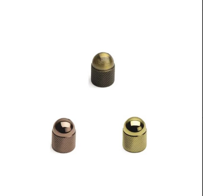 May include: Three metal knobs with a round top and a knurled base. The knobs are in antique brass, polished brass, and copper finishes.
