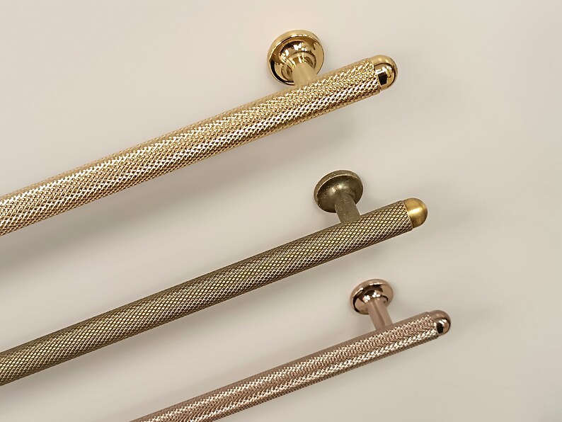 May include: Three different metal cabinet pulls with a textured finish. The pulls are in gold, bronze, and rose gold.