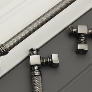May include: Three black nickel cabinet pulls with a diamond pattern. The pulls have a square base and a round knob.