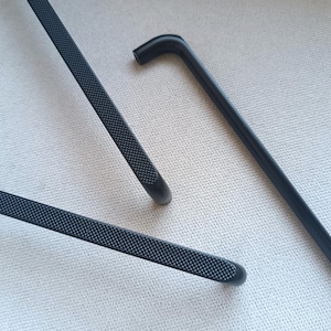 May include: Three black metal cabinet door pulls with a textured finish. The pulls are in different shapes and sizes.