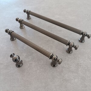 May include: Three black metal cabinet pulls with a fluted design and a round knob at each end. A smaller black metal knob is also shown.