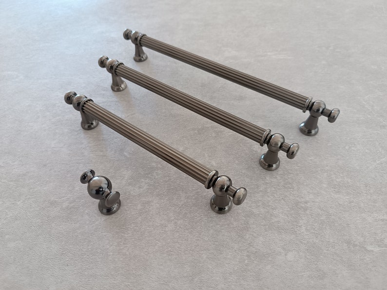 May include: Three black metal cabinet pulls with a fluted design and a round knob at each end. A smaller black metal knob is also shown.