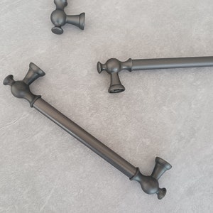 以下が含まれることがあります： 丸みを帯びた端を持つ黒い金属製のキャビネットドアプルが3つあります。2つのプルは短く、1つは長いです。