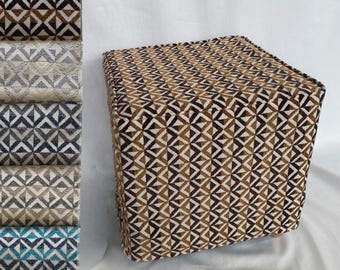 May include: A square ottoman upholstered in a fabric featuring a repeating geometric pattern of triangles in shades of brown, cream, and black. To the left, a vertical stack of fabric swatches displays the same pattern in various colorways.