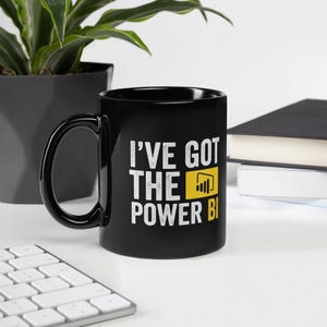 May include: Black coffee mug with a white graphic that says "I've got the power BI" with a yellow Power BI logo.