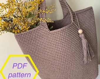 May include: A brown crocheted tote bag with a wooden bead and tassel. The bag is large enough to hold a bouquet of yellow mimosa flowers. The image includes the text "PDF pattern".