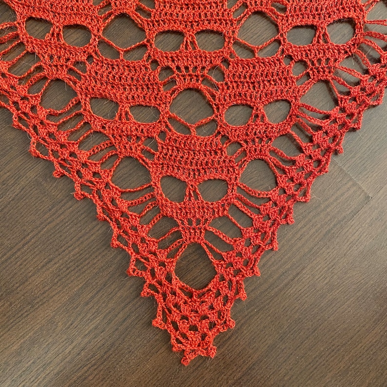 Puede incluir: Primer plano de una chal de ganchillo con un patr&oacute;n de calavera en color naranja oscuro.