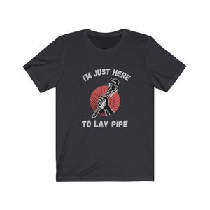 May include: A black t-shirt with a white graphic of a hand holding a wrench with the text "I'm just here to lay pipe".