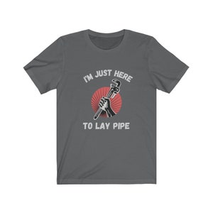 May include: A dark gray t-shirt with the text "I'm just here to lay pipe" and a graphic of a hand holding a wrench.