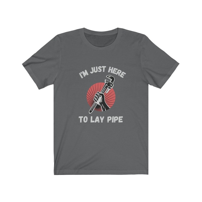May include: A dark gray t-shirt with the text "I'm just here to lay pipe" and a graphic of a hand holding a wrench.