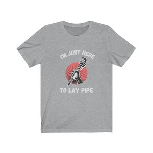 May include: A gray t-shirt with the text "I'm just here to lay pipe" and a red circle with a wrench in it.