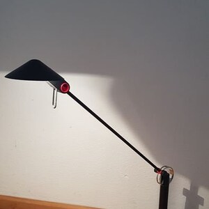 May include: A black desk lamp with a long, adjustable arm and a black shade. The lamp has a red switch and a black cord.
