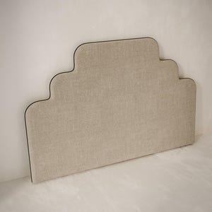 Puede incluir: Una cabecera beige con un diseño único, curvo y en capas. La cabecera tiene un ribete negro alrededor de los bordes.