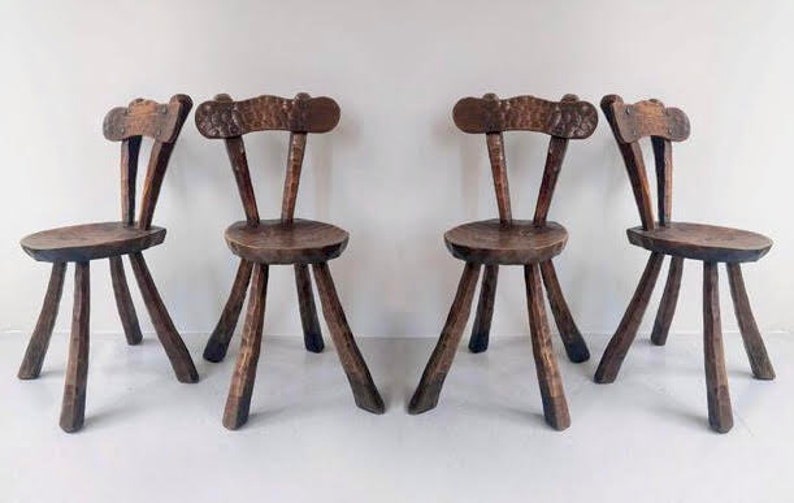 May include: Set of four rustic wooden chairs with a simple design. Each chair has a carved wooden seat and back, and four sturdy legs.