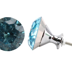 May include: A blue crystal cabinet knob with a silver base and a screw. The crystal is faceted and has a diamond shape.