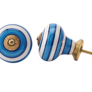 May include: Two blue and white striped ceramic cabinet knobs with a gold accent. One knob is round and the other is a rounded rectangle with a screw.