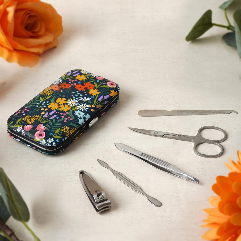 May include: A floral patterned nail clipper set with a variety of tools, including a nail clipper, tweezers, a cuticle pusher, a nail file, and scissors. The tools are all silver and are laid out on a white surface.