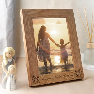 May include: A wooden photo frame with a light brown finish. The frame features a photo of two people walking on a beach. The frame has an engraved message that reads "If mums were flowers, I'd pick you".