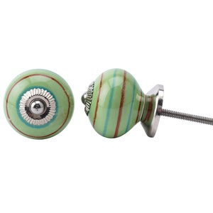 May include: Two green and red striped ceramic cabinet knobs with silver accents. One knob is attached to a silver screw.