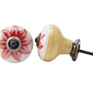 May include: Two ceramic drawer knobs with a floral design. One knob is yellow and white with a red flower. The other knob is white with a red flower. Both knobs have a silver screw.