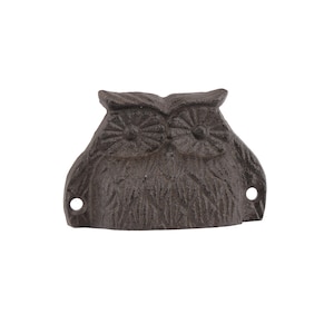 May include: A cast iron owl bottle opener with a rustic brown finish. The owl has detailed eyes and feathers.