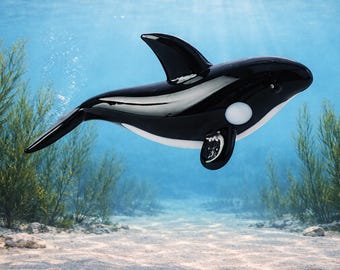 May include: A black and white orca figurine with a glossy finish. The orca has a white belly, a white spot near its eye, and black fins. The figurine is suspended in water with sunlight filtering through, creating an underwater scene.