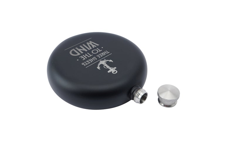 May include: Black metal flask with a silver screw-on cap. The flask has an engraved anchor and the text "Three Sheets To The Wind."