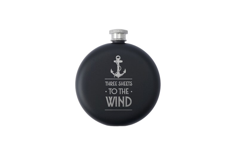 May include: Black flask with a silver lid and an engraved anchor with the text "Three Sheets To The Wind".