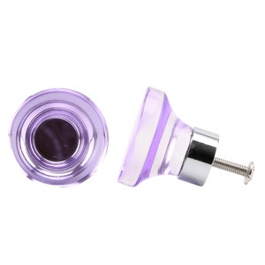 May include: Two purple glass cabinet knobs with a silver metal base and screw.