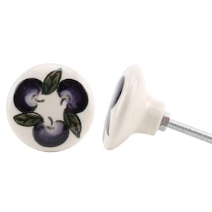 May include: A white ceramic knob with a purple and green floral design. The knob has a silver screw.