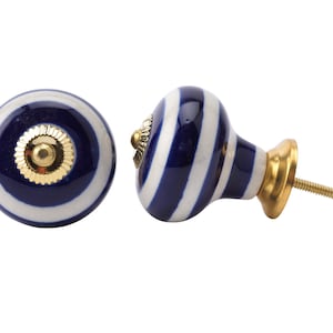 May include: Two blue and white striped ceramic cabinet knobs with gold accents. One knob is shown with a screw.