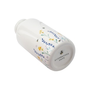 May include: White ceramic jar with a floral and bee design. The jar is dishwasher safe.