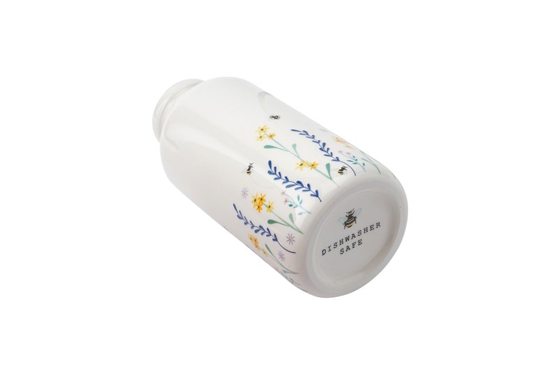 May include: White ceramic jar with a floral and bee design. The jar is dishwasher safe.