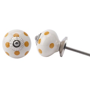 May include: White ceramic knob with yellow polka dots and a silver screw. The knob is shown from two angles.