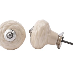 Peut inclure: Deux boutons de cabinet en céramique blanc cassé avec un motif floral en relief. Un bouton a une vis argentée et l'autre a une base argentée avec une vis.