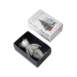 May include: A small white mouse wearing a striped pajama-like outfit is inside a blue box with white stars. The box is open and the lid is white with the text "The Night Before Christmas" in gold lettering. The lid also features a small illustration of a mouse decorating a Christmas tree.