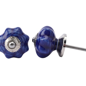 May include: Two decorative cabinet knobs. The knobs are a deep blue with a marbled effect and a silver-coloured metal base. One knob has a flower-like shape, and the other is rounded. The screw is approximately 5 cm long.