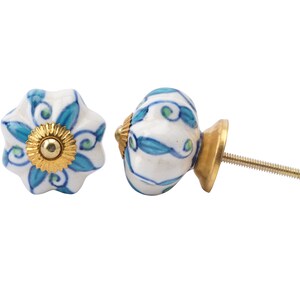 May include: Two ceramic cabinet knobs with a white background and blue and green floral designs. One knob has a gold screw and the other has a gold base and screw.