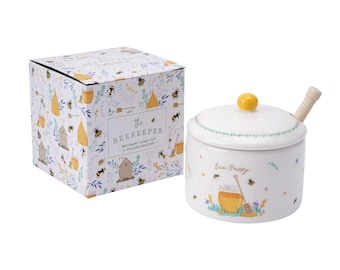 May include: White ceramic honey pot with a wooden dipper and a yellow lid. The pot has a bee-themed design with the text "Bee Happy" and a beehive illustration. The pot comes in a box with a bee-themed design and the text "The Beekeeper Bee Happy Honey Pot & Wooden Dipper".