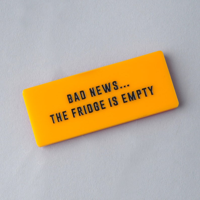 Op de afbeelding: Een geel rechthoekig bord met de tekst "BAD NEWS... THE FRIDGE IS EMPTY" in zwarte letters.