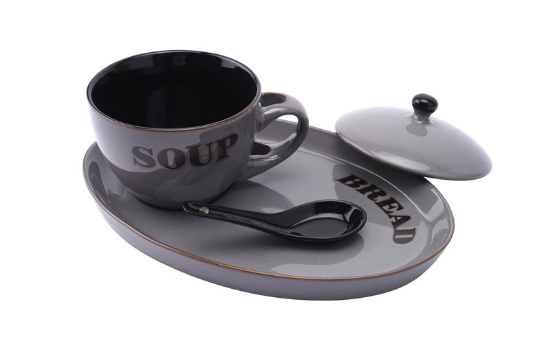 May include: Grey ceramic soup bowl with a black interior and the word "SOUP" printed on the side, a grey ceramic bread plate with the word "BREAD" printed on the side, a grey ceramic lid, and a black ceramic spoon.