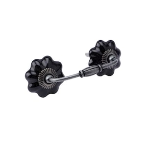 May include: Black ceramic drawer pull with a silver metal arm. The pull has a flower-shaped design.