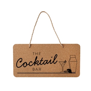 Könnte beinhalten: Ein Korktafel-Schild mit einem Seilhalter, auf dem in schwarzer Kursivschrift "The Cocktail Bar" steht. Auf dem Schild sind ein Cocktailglas mit einem Limettenkeil und ein Cocktailshaker abgebildet.