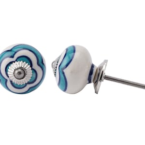 Puede incluir: Pomo de armario de cerámica blanca con un diseño floral azul y blanco. El pomo tiene un tornillo y una base plateados.