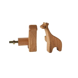 Könnte beinhalten: Zwei tierförmige Knöpfe aus Holz, einer in Form einer Giraffe und der andere in einfacher rechteckiger Form mit einer Schraube. Die Knöpfe sind hellbraun und eignen sich für den Einsatz an Möbeln.