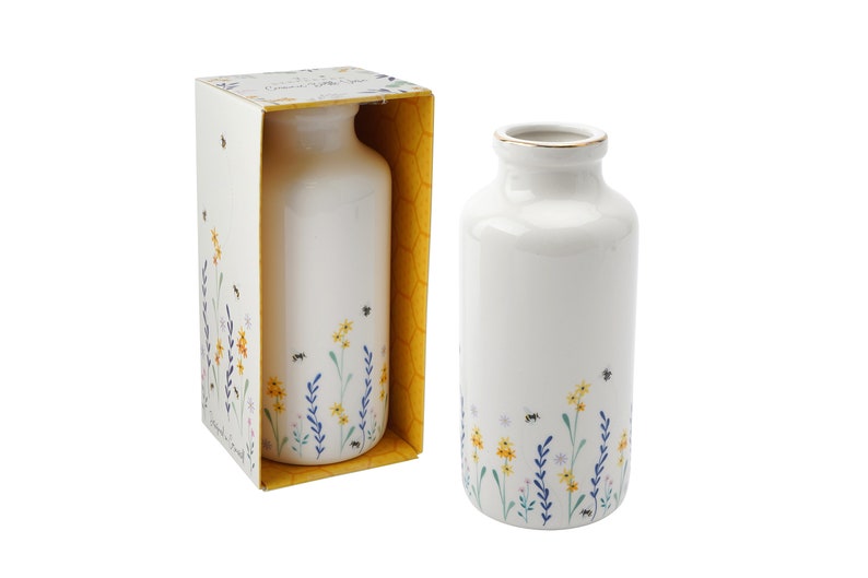May include: Two white ceramic vases with a floral and bee design. The vases are in a box with a honeycomb pattern.