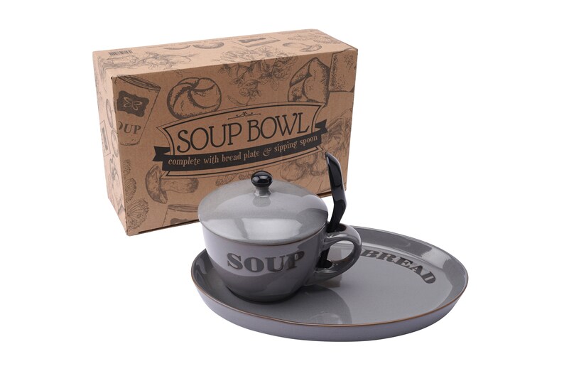 May include: A grey ceramic soup bowl with a lid and a matching bread plate. The bowl has the word "Soup" printed on it and the plate has the word "Bread" printed on it. The set comes in a brown cardboard box with a design of bread and other food items.